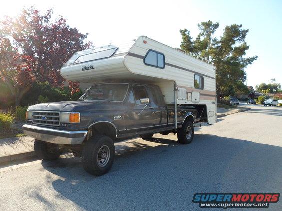 Dark blue Ford F-250 with camper, 3q-front view. Visible "F-250" badge