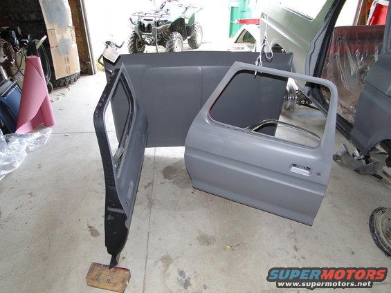 Gray vehicle doors and bed panel disassembled in garage. ATV in background