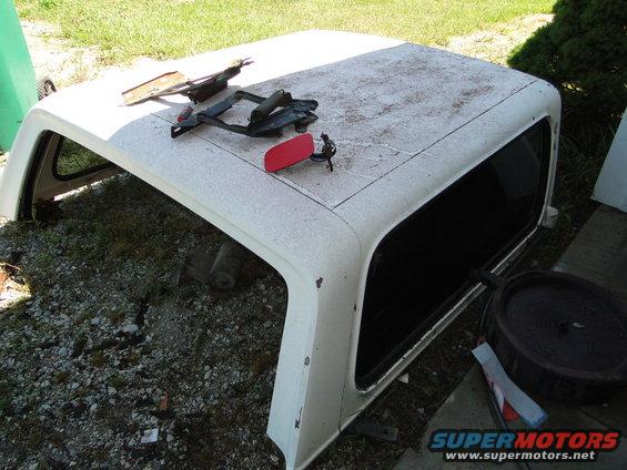 White Ford Bronco hardtop sitting outside with some parts on top