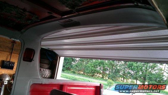 Interior view of a red truck bed with a spare tire, looking out an open garage door
