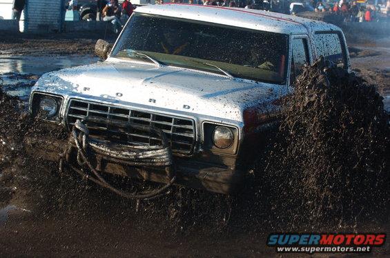 Ford Bronco stuck in mud pit, front grille visible, winch cable attached