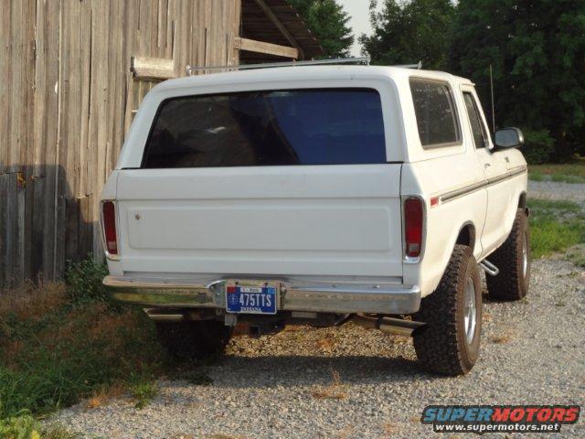 Rear view of a white 1978 Ford Bronco parked next to a wooden building