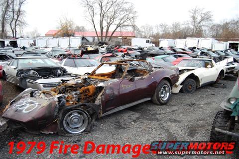 Maroon 1979 Corvette with extensive fire damage in a junkyard
