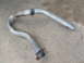 1984 Ford Bronco - A bent exhaust pipe lies on a concrete surface. The registry claims it is from a 1984 Ford Bronco, but this is unconfirmed.