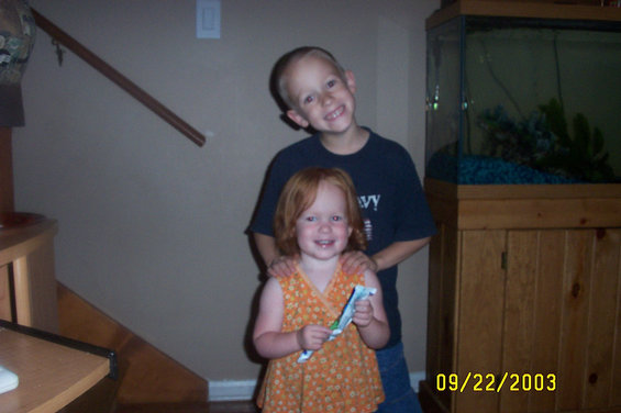 Boy and girl smiling in front of a staircase and aquarium. Date stamp reads 09/22/2003
