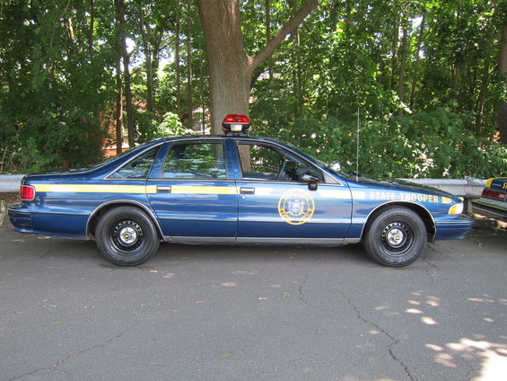Side view of blue 1991 Chevrolet Caprice police car with yellow stripe and "STATE TROOPER" text