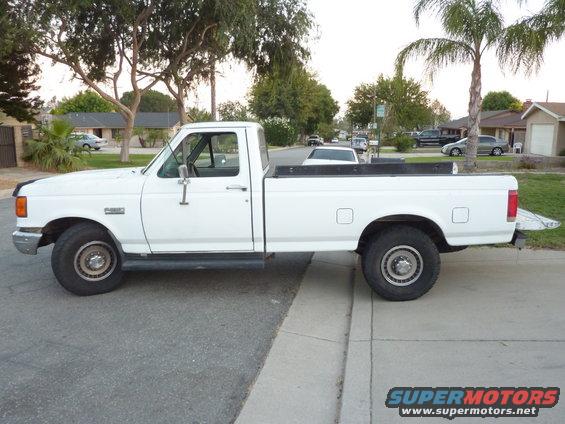 Side view of a white 1987 Ford F-250 pickup truck parked on a residential street