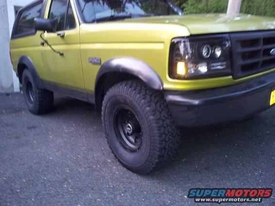 Yellow 1992 Ford Bronco front quarter view. Black fender flares and aftermarket headlights are visible