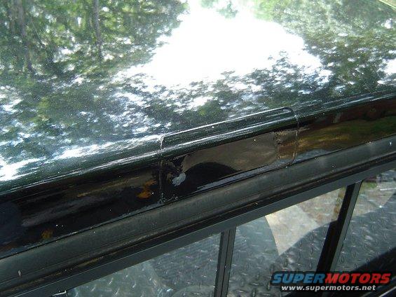 Black truck bed rail with peeling paint and a small dent