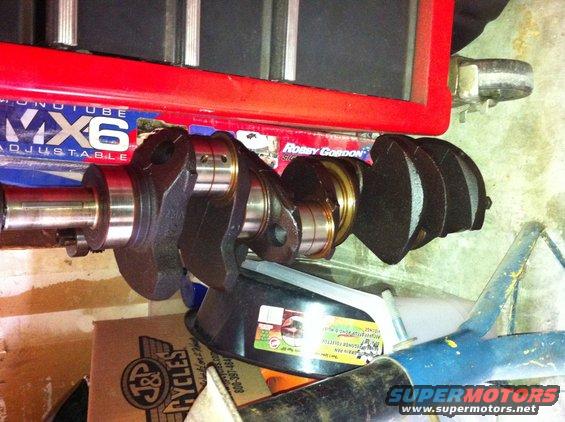 Crankshaft with counterweights and bearings, resting on a funnel. A red toolbox is above