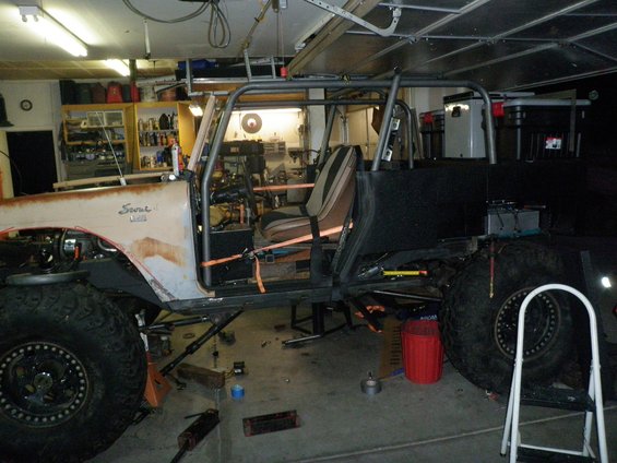 1961 International Scout 800 with custom roll cage, rusty body, and large tires in a garage