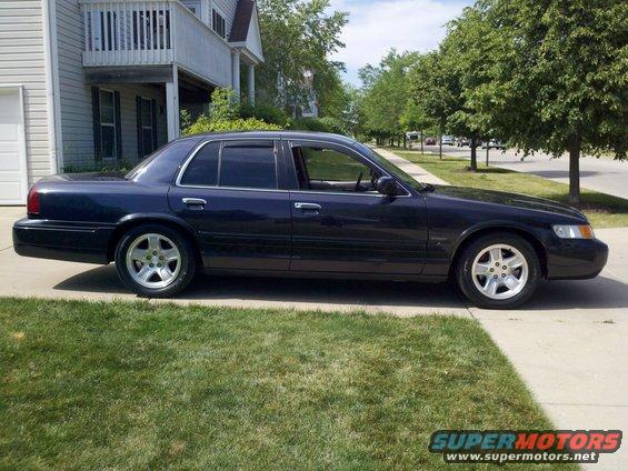 dark blue sedan parked on a driveway, side view