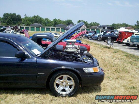 1999 Mercury Grand Marquis with hood open, showing engine. Other cars parked in background