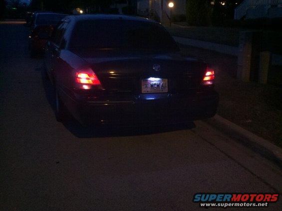 Dark sedan's rear end with illuminated license plate reading MGM 6