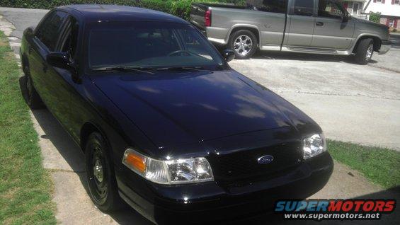 Black sedan parked on a driveway, silver pickup truck behind it