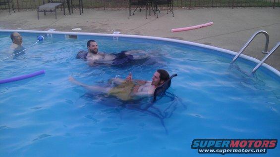 Guys relaxing in a pool with pool noodles and floats