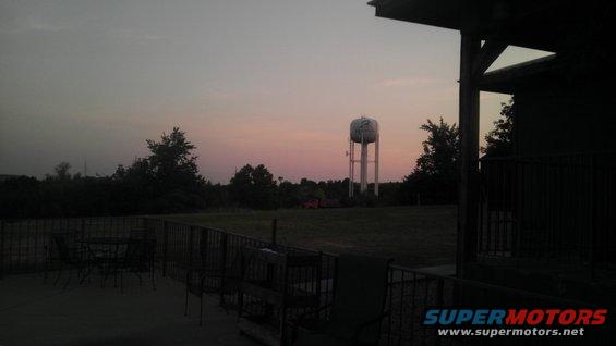 Water tower in a field at dusk, with a porch in the foreground