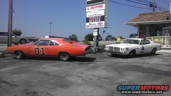 Orange 1970 Dodge Charger with "01" on door, parked next to a white police car