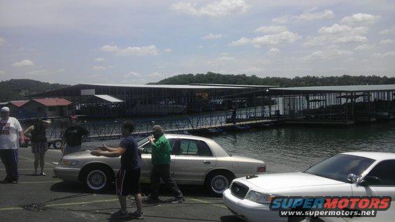 Silver sedan parked by a lake with a marina in the background