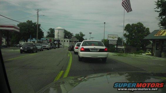 white police car in traffic, looks like a Crown Victoria