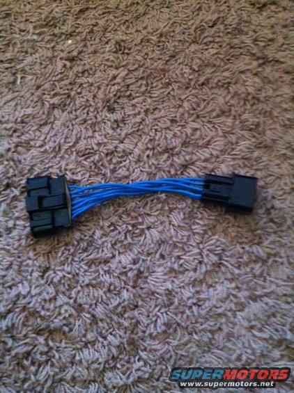 Wiring harness adapter with blue wires and black connectors on a carpeted surface