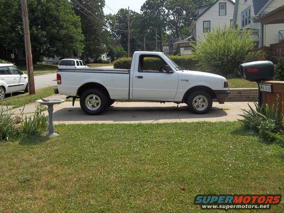 White Ford Ranger pickup truck parked in driveway, another SUV and a white SUV in background