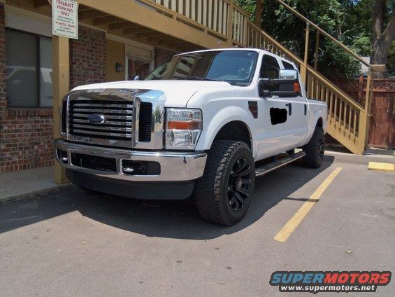 White Ford F-Series pickup truck parked outside a building with wooden stairs