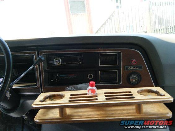 1988 Ford E350 Chateau interior with wood-grain trim, aftermarket radio, and a wooden tray holding a bottle