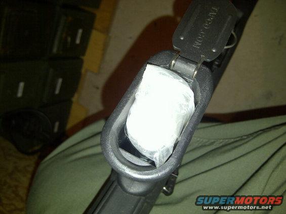 Gun magazine well with white plastic bag inside, "TAPCO.COM" visible on latch, "SUPERMOTORS.NET" watermark
