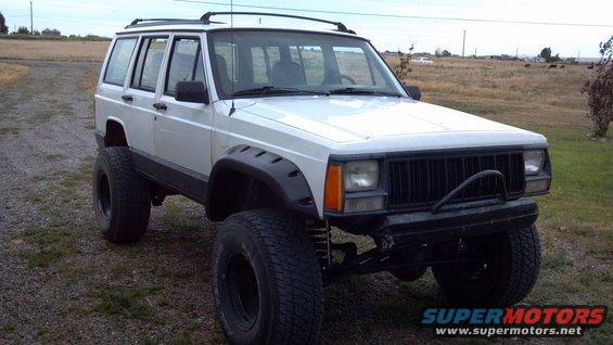 White 1995 Jeep Cherokee with lifted suspension and oversized tires, viewed from a 3/4 front angle