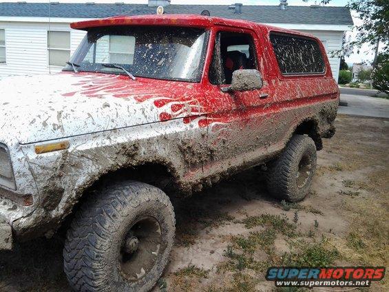 Mud-covered red SUV with flame decals. Looks like a 1979 Ford Bronco
