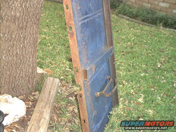 Blue door leaning against a tree, showing rust and a metal handle