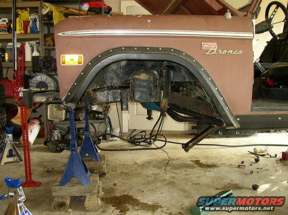 Ford Bronco body on jack stands, showing suspension and fender. "Bronco" script visible