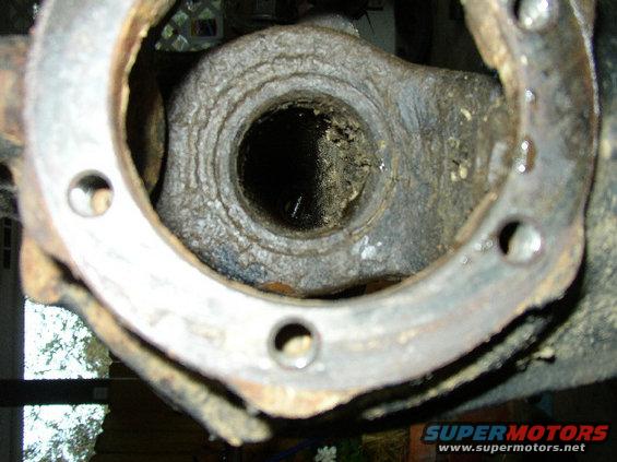 Rusted metal part with a circular opening and bolt holes