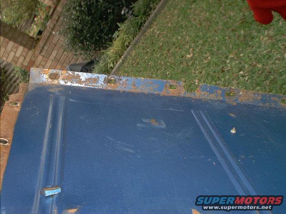 Blue metal panel with rust along the top edge and mounting holes