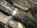 1989 Ford Bronco - Undercarriage view shows driveshaft and exhaust system components, heavily coated in mud.