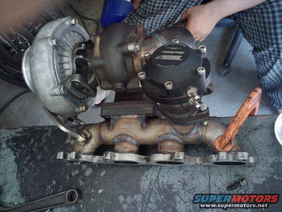 Turbocharger and exhaust manifold assembly with a black wastegate actuator. Text on actuator reads 'Turbosmart'