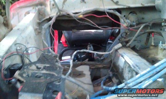 view into vehicle engine bay with exposed wires and parts