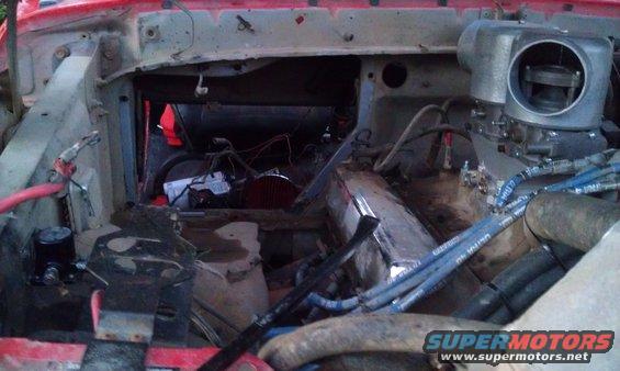 Engine bay with red paint, exposed wires, and a large carburetor
