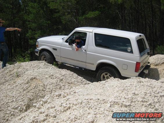 White Ford Bronco driving over a pile of light-colored rocks