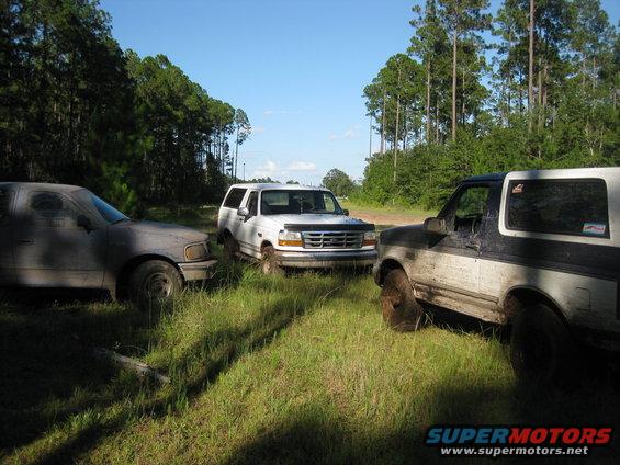 1994 Ford Bronco front grille and side view, parked with two other SUVs in a grassy area