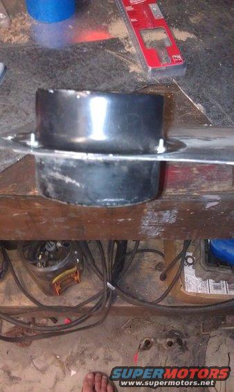 Black AC ductwork attached to metal plate, with Milwaukee level and Supermotors logo