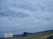 1992 Ford Taurus - Sign for South Dakota Mount Rushmore faces against a cloudy sky and rolling hills.
