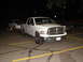1992 Ford Taurus - A white Dodge Ram pickup truck is parked at night, towing a white car on a trailer.