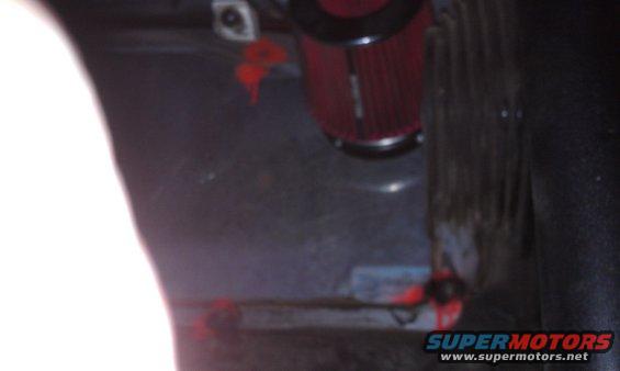 Red air filter with black trim, mounted in a dark interior space