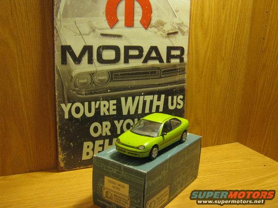 Green toy car on a box in front of a Mopar sign. Box says 'Dodge Neon'