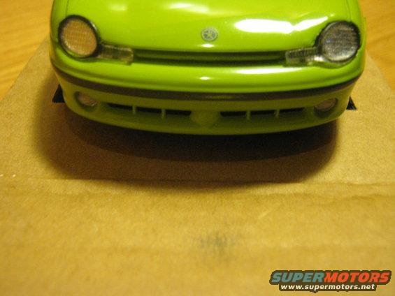 Green toy car front bumper with circular headlights and horizontal grille openings