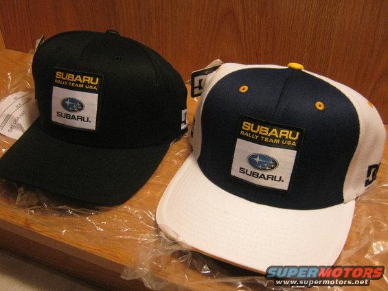 Two Subaru baseball caps, one black and one white/blue, with Subaru Rally Team USA patches