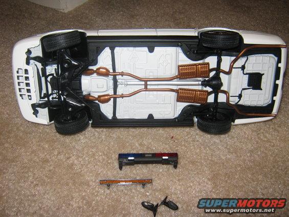 Underside of white car model with separate police light bar and mirrors