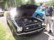 1978 Ford Mustang II - A black 1978 Ford Mustang II is displayed with its hood open at a car show, with people observing.